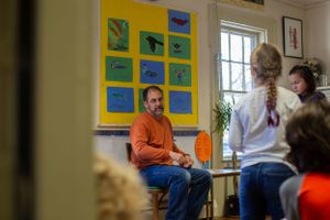 A classroom discussion with colorful animal artwork displayed on yellow walls.