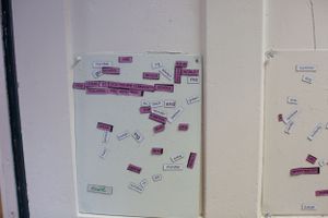 A white board with scattered pink and white word magnets arranged randomly.