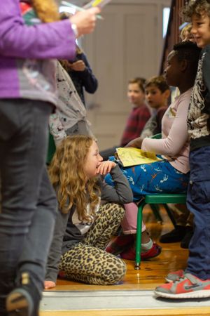 Children gathered on wooden floor with colorful clothing during indoor activity.