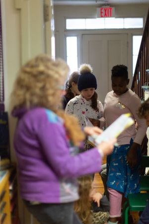 Group of students participating in classroom activities with purple-clad teacher.
