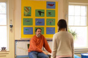 A conversation taking place in a classroom beneath decorative nature-themed artwork on yellow background.