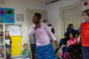 Students engaged in movement activities in a classroom with artwork on walls.