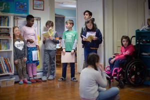 Children spread out in a classroom during an interactive learning activity.
