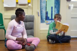 Young students practicing reading independently in a colorful classroom setting.