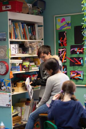 Students working at desks in a classroom with green walls and colorful artwork displays.