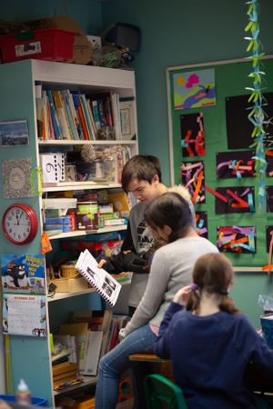 Classroom scene showing students studying at desks with bookshelves and art on walls.