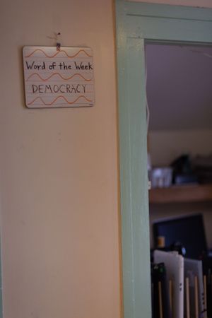 Classroom wall with signs including 'Word of the Week' and 'Democracy' mounted.