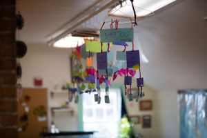 Colorful paper crafts and decorations hanging from classroom ceiling.