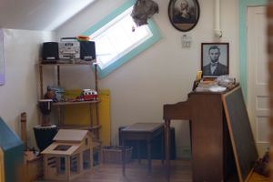Educational room interior with framed portraits and furniture against white walls.