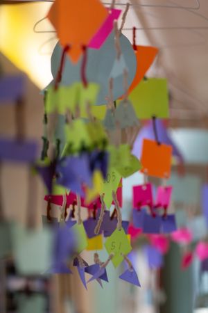 Colorful paper decorations and shapes hanging from above create a blurred artistic mobile display.