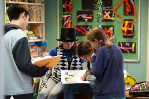 Students gathered around a table in a classroom with artwork displayed on walls.