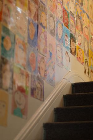 Stairway wall decorated with colorful children's artwork and drawings.