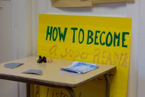 Yellow sign on desk reads 'How to Become a Super Reader'.