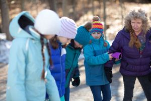 A group walks together on a winter trail wearing colorful winter coats and hats.
