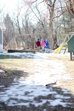 People walking down a snowy path between buildings on a winter day.