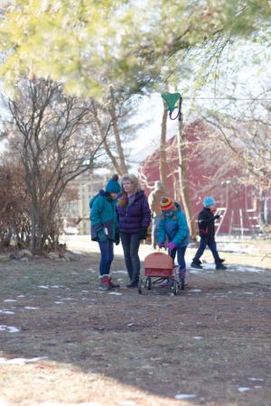 Group playing outdoor winter games in a yard with a red barn visible in the background.