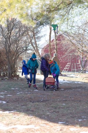 People enjoying outdoor winter activities near a red barn structure.