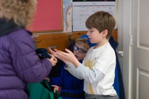 Students participating in an indoor classroom activity with red walls.