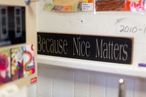 Classroom wall displays a colorful sign with text 'Because Nice Matters' above student artwork and materials.