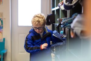 Students in blue uniforms working at classroom workstations with tools and equipment.