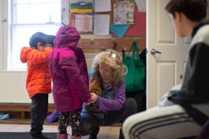 Students in winter coats gathering near classroom entrance during arrival time.