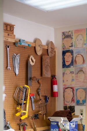 Pegboard wall display with wooden crafts and tools organized in a classroom workshop setting.