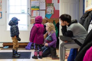 Students removing winter boots and coats in school entrance area.