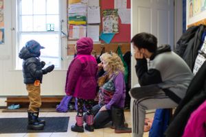 Children organizing their winter gear and boots in school entryway.