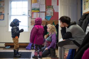 Students arranging winter clothing and footwear in school entrance area.