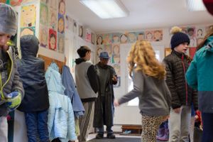Group of students in winter attire gathering in classroom entrance area.