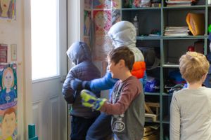 Students working together in a classroom with shelves of learning materials and toys.