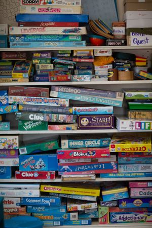 Large collection of classic board games and puzzles stacked on shelves including Clue, Monopoly, and other favorites.