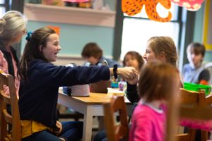 Students participating in classroom activities with bright orange decorations visible.