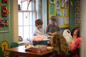 Bright classroom environment with children working at tables and colorful artwork displayed on walls.