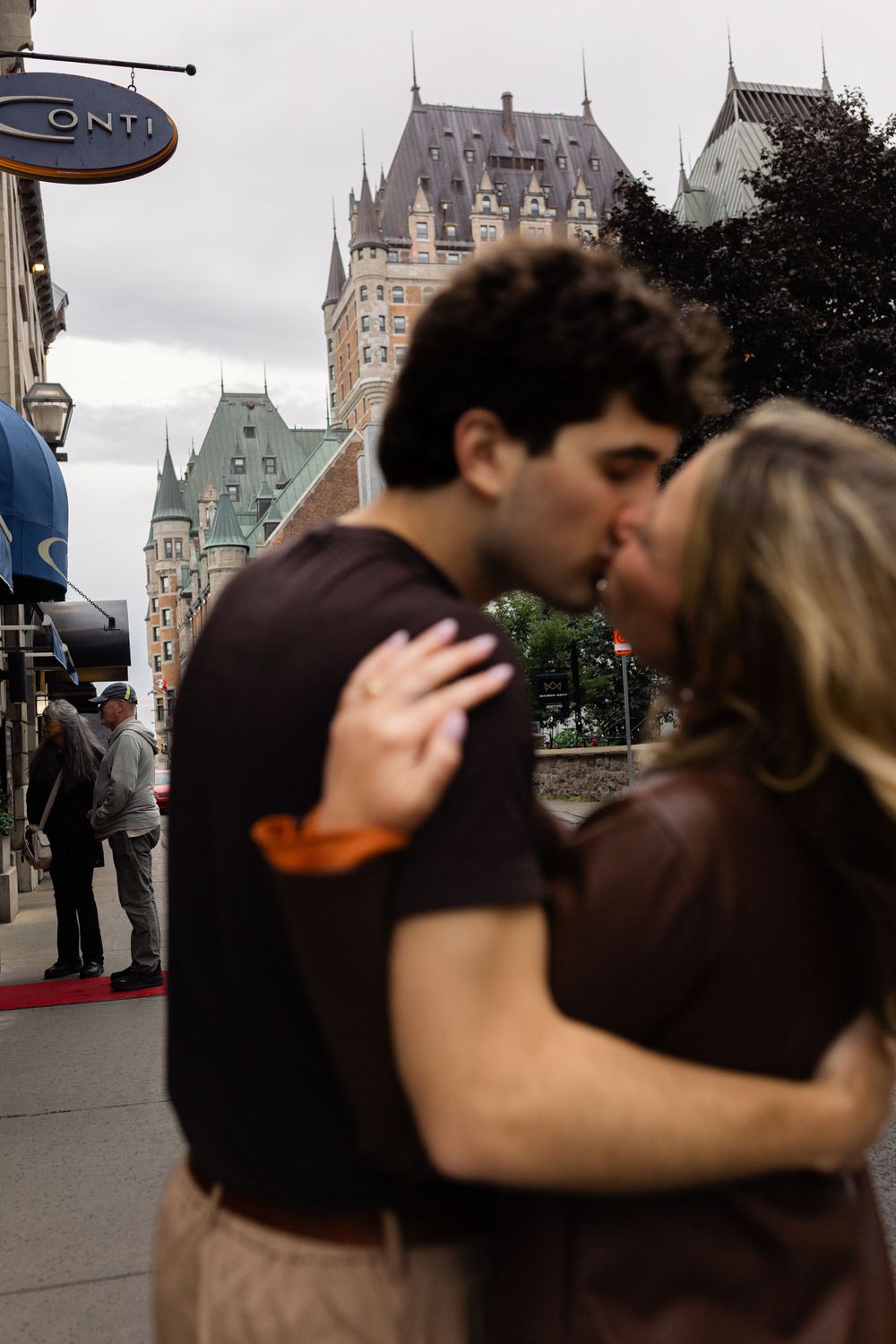 Couple kissing on a street in Old Quebec City with Chateau Frontenac castle in the background.