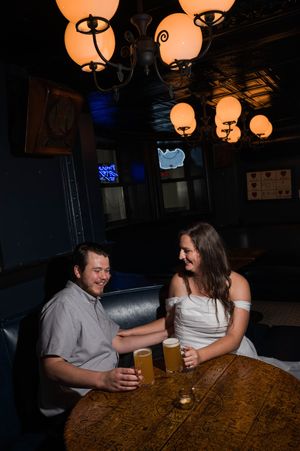 A couple shares drinks and conversation at a dimly lit bar with orange pendant lights overhead. Graduate Hotel by Hilton New Haven Old Heide