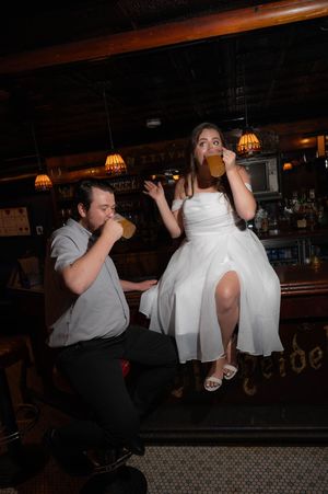 Two people share a fun moment while drinking at a bar counter. Graduate Hotel by Hilton New Haven Old Heidelberg Bar