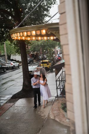A couple dances on a rainy sidewalk under glowing paper lanterns at dusk. Graduate Hotel by Hilton New Haven