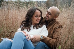 Couple shares tender moments among tall autumn grasses during photoshoot.