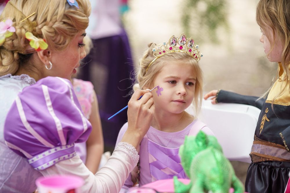 Photo from kids birthday party of a young girl getting face paint put on
