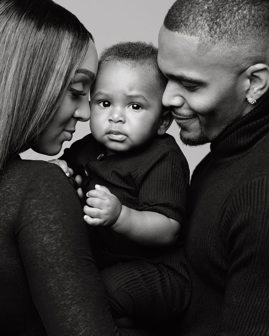 Black and white portrait of a loving family, parents tenderly holding their baby boy in a studio setting.