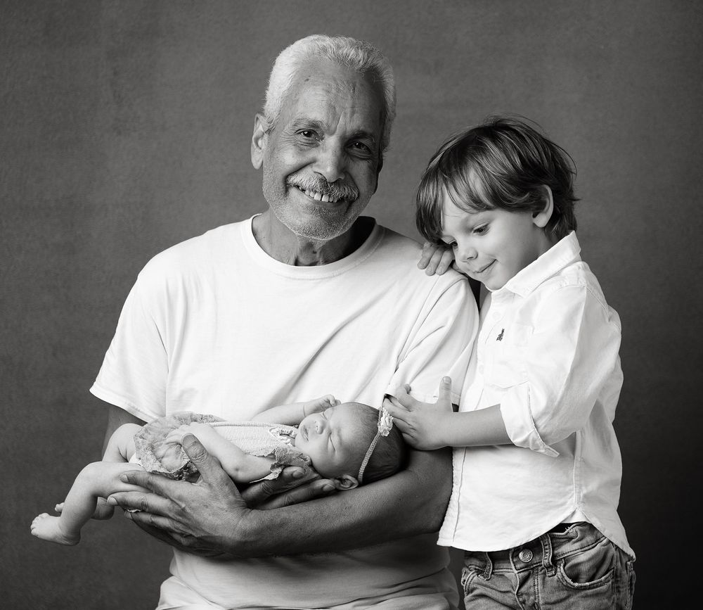 A black and white portrait of three generations together sharing a tender moment.