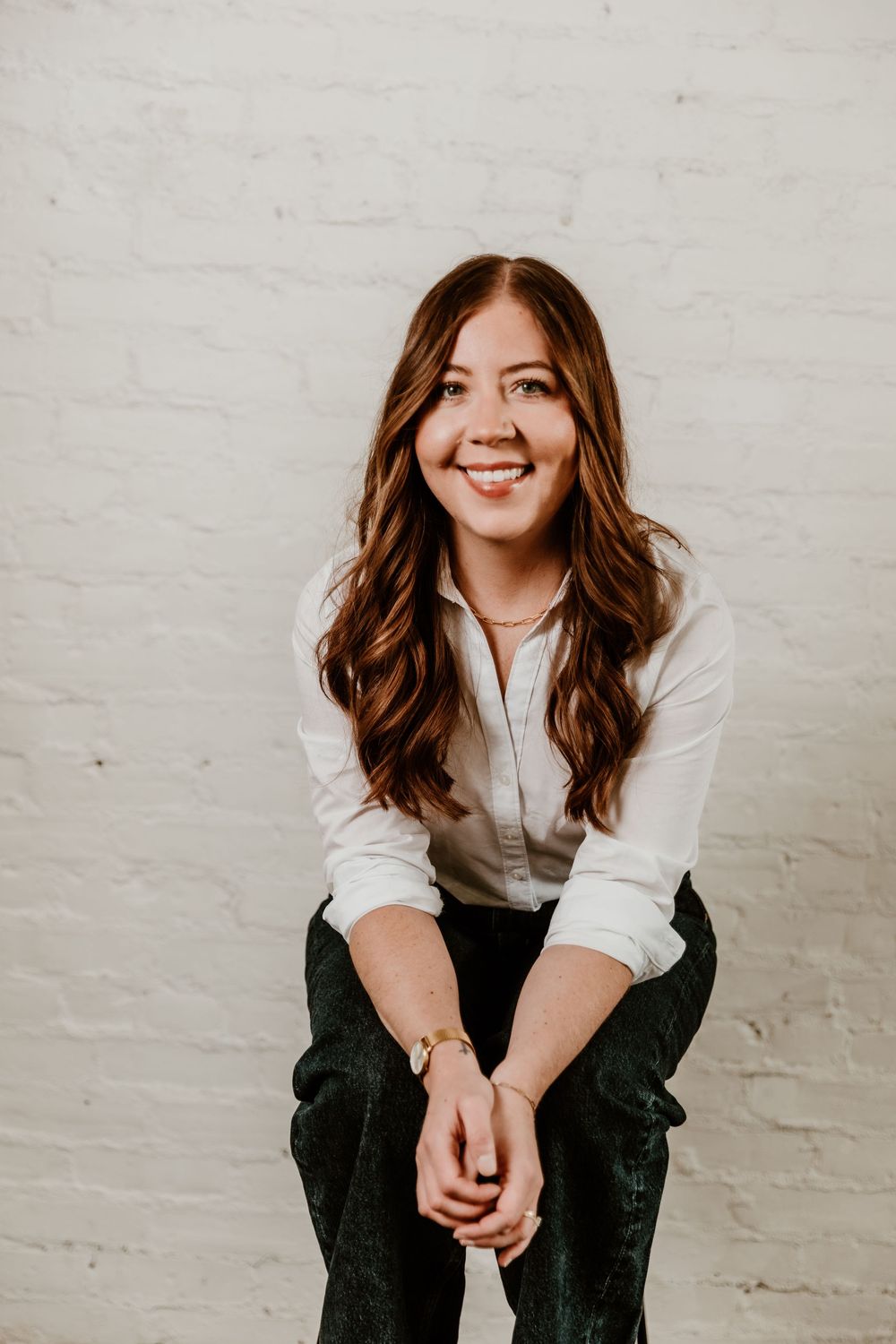 Professional headshot portrait series showing warm expressions against white brick wall background.