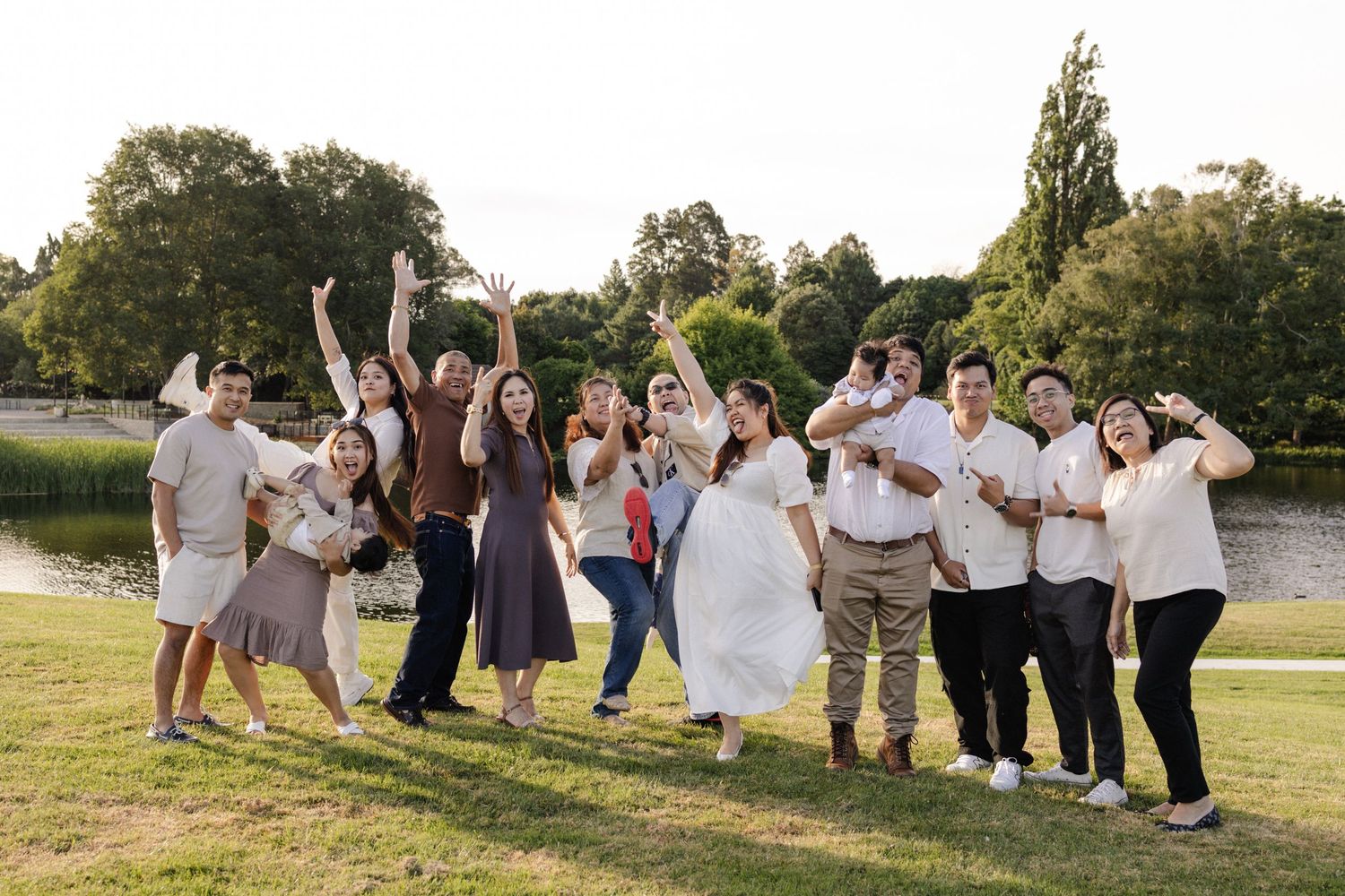 Large family group photo with multiple generations gathered on a wooden fence in a pastoral setting.