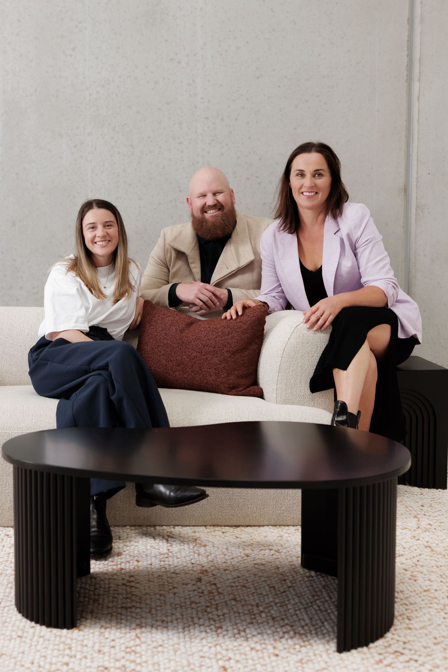 A photo of a professional team sitting down on a dark curved modern coffee table.