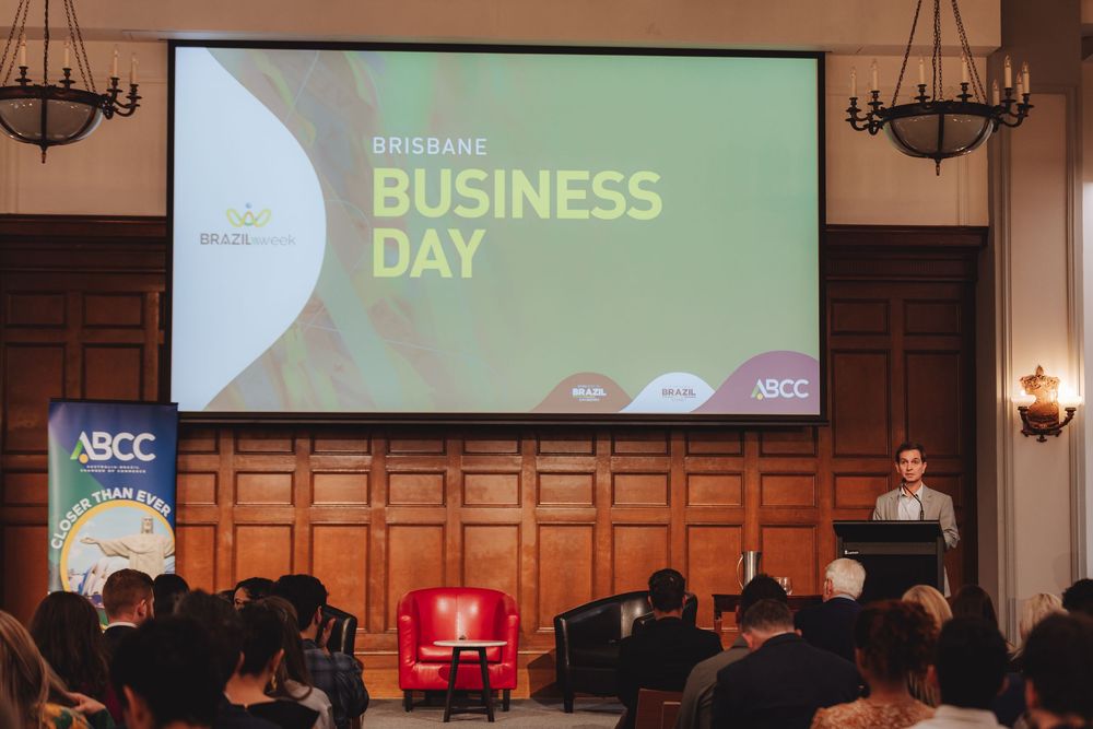 Business conference presentation shown on large screen in elegant wood-paneled auditorium venue.