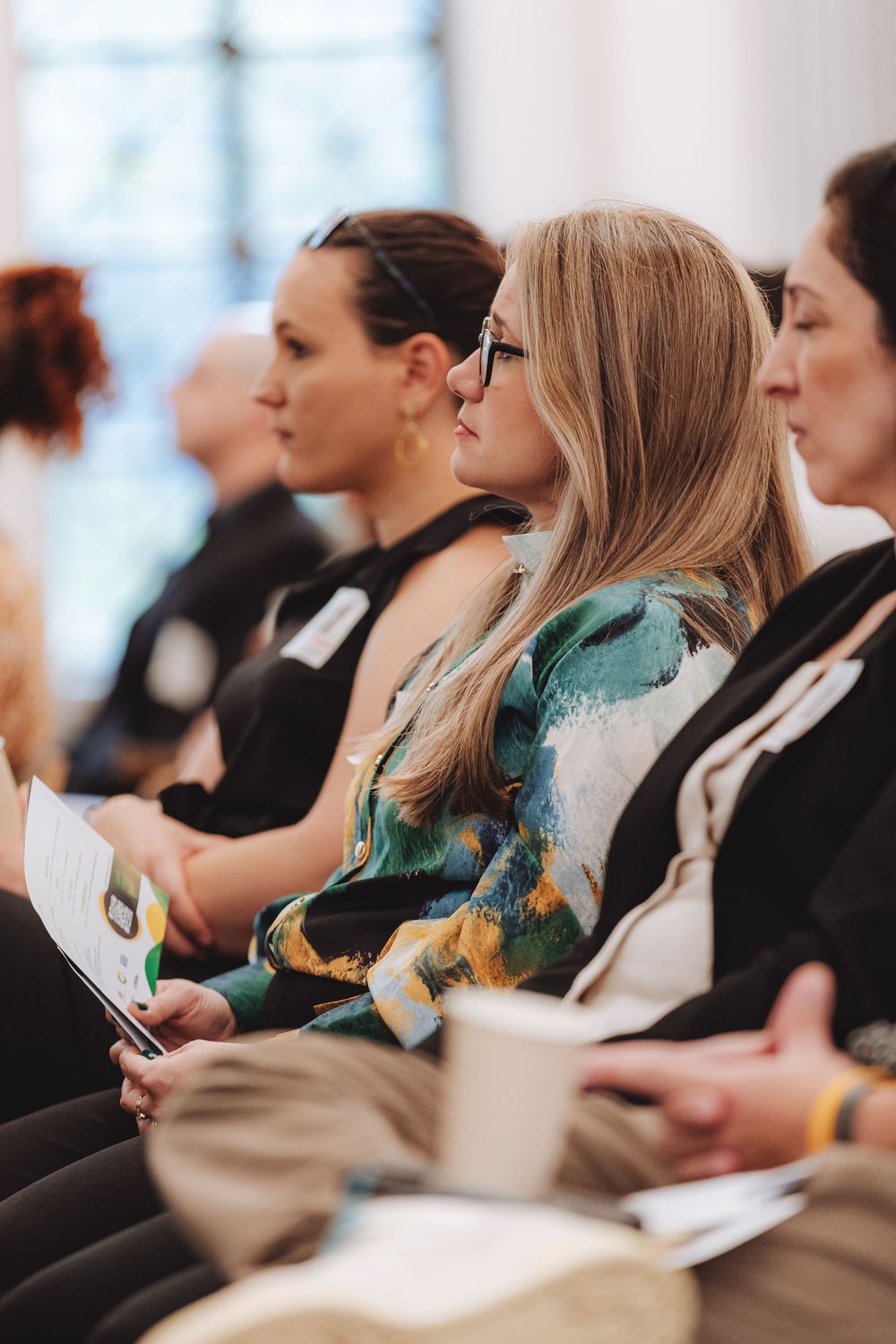 Row of attendees taking notes during a professional conference or seminar presentation.