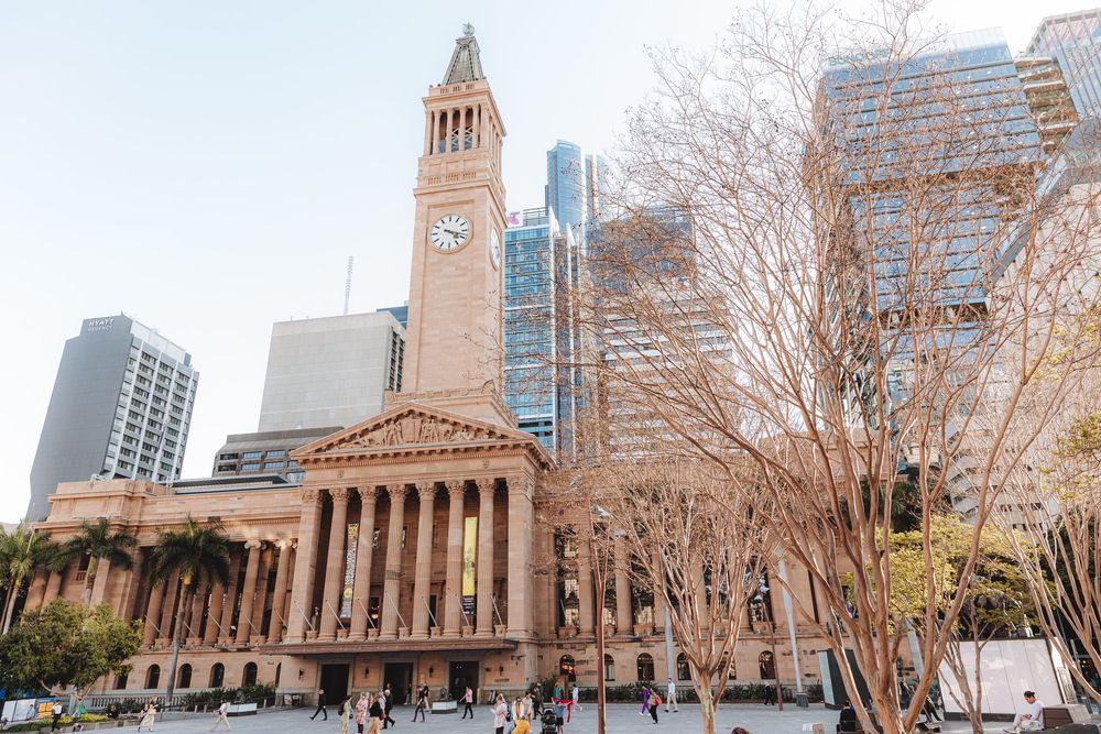 Brisbane City Hall and surrounding modern buildings viewed through bare winter trees.