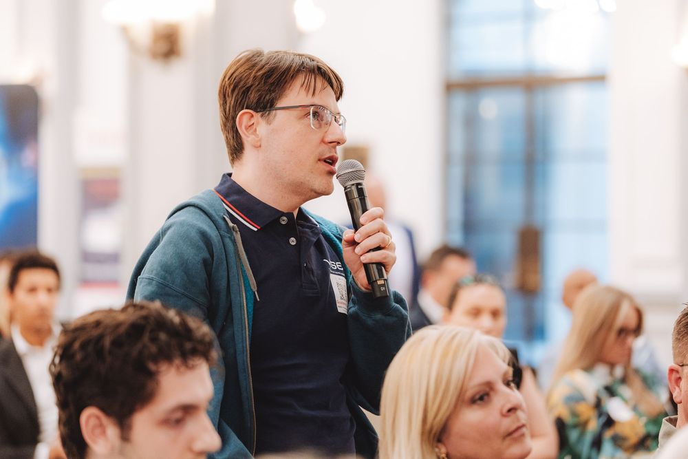 A group of professionals listening attentively during a business conference presentation in a bright modern space.