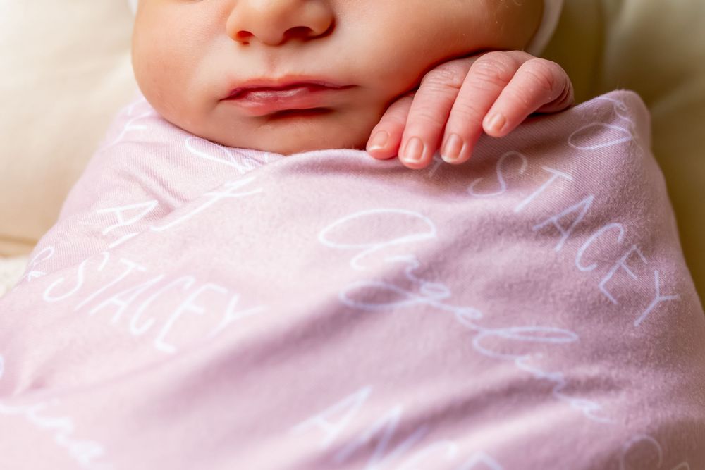 A series of soft pink baby blankets or swaddles arranged in a horizontal row showing different textures and folds.